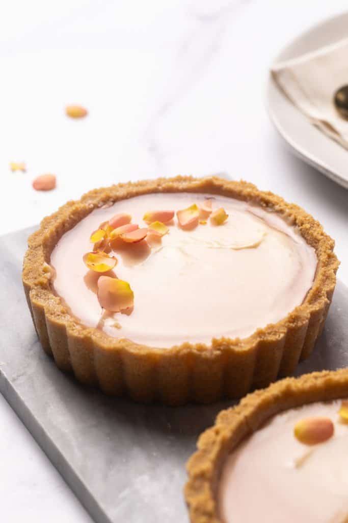 Two mini cheesecake tarts on a marble plate.
