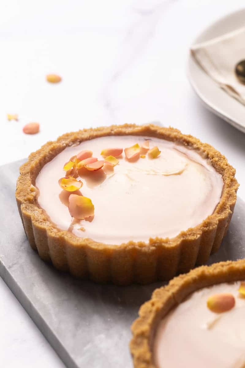 Two mini cheesecake tarts on a marble plate.