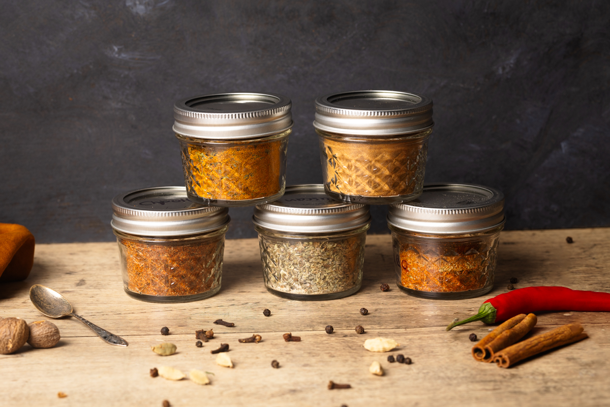 A stack of homemade spices next to whole spices.