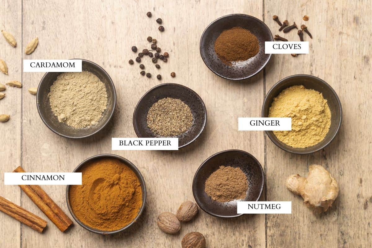Ground spices in little bowls laid out next to whole spices.