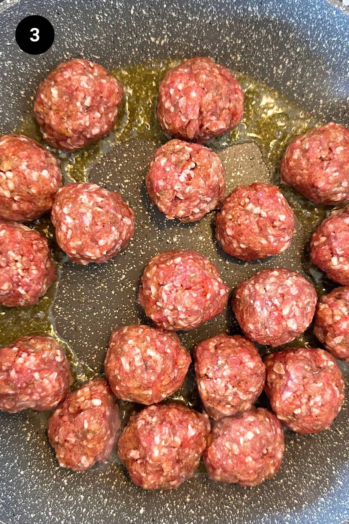 Meatballs being fried in a pan.