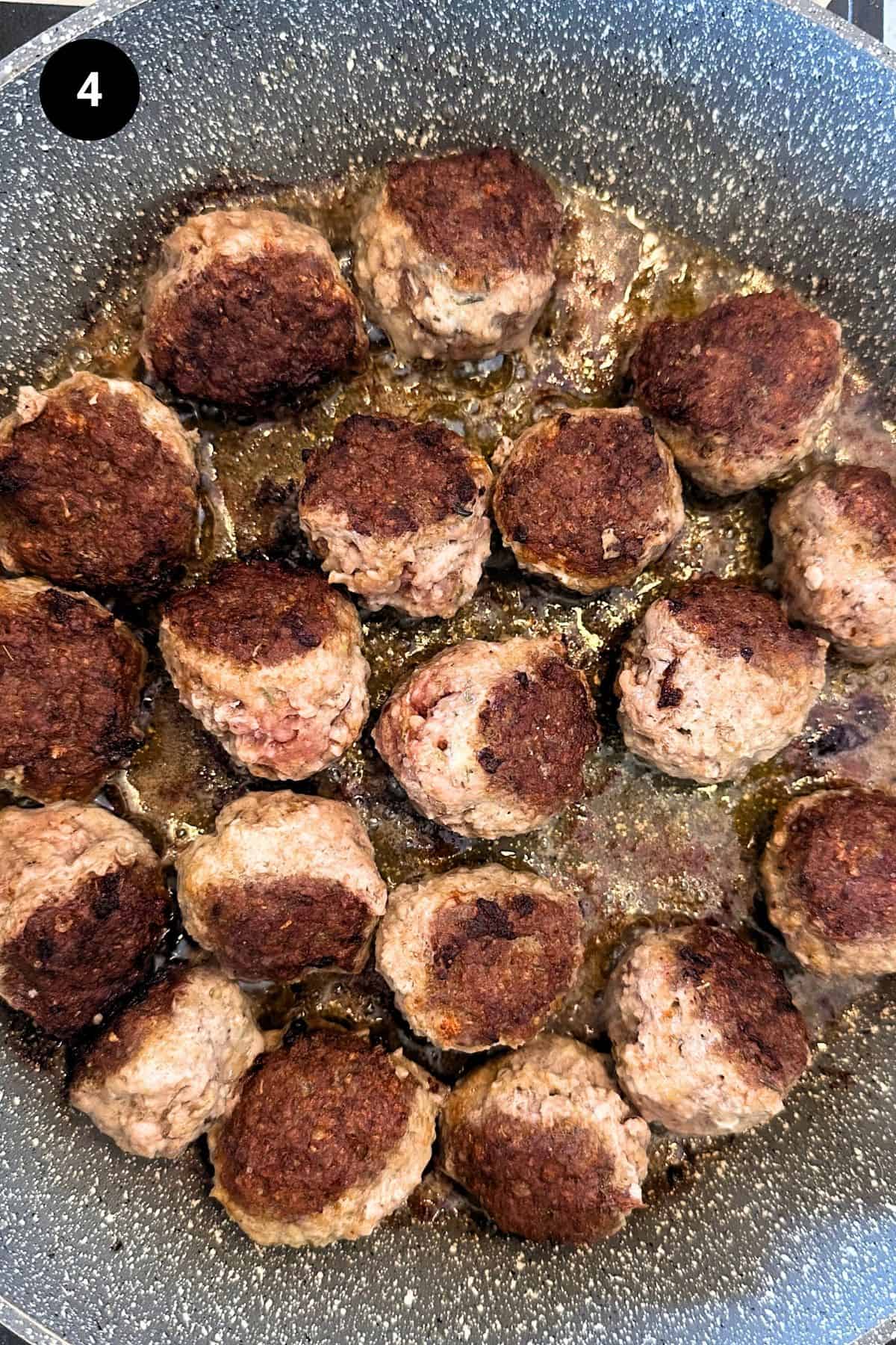 Meatballs being fried in a pan.
