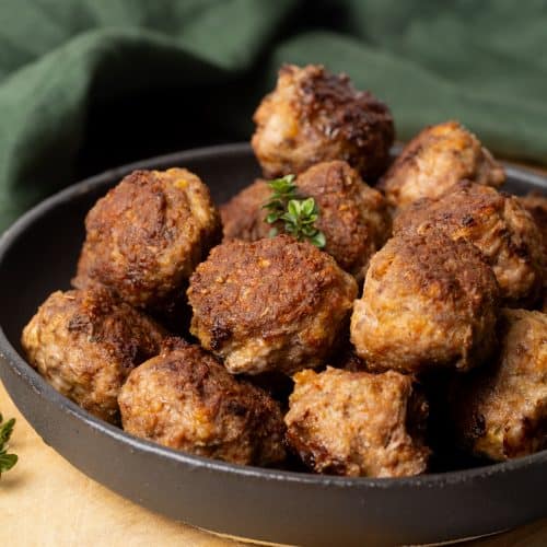 A black plate with lamb meatballs in a wooden board.