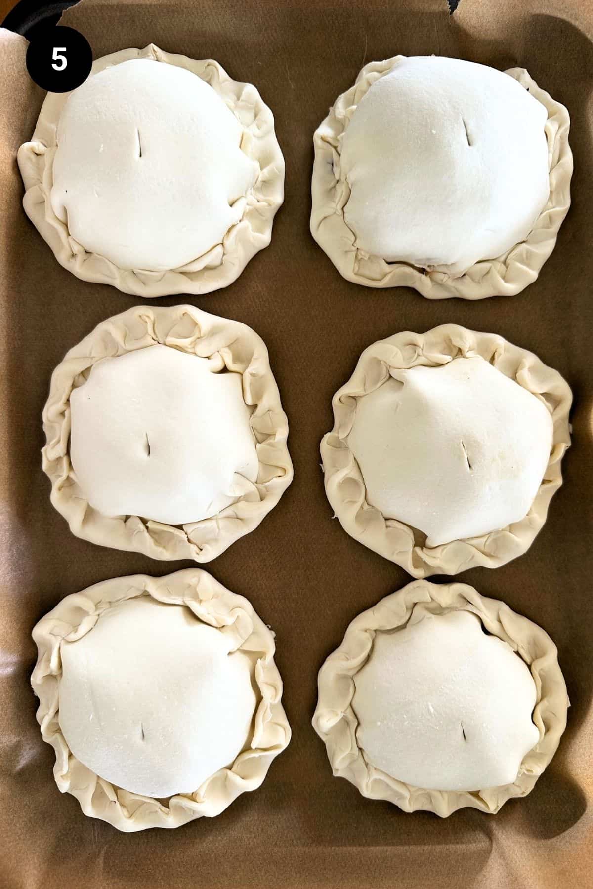 Unbaked lamb wellingtons on a baking tray.