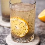 Two glasses with chia lemonade on marble coasters next to half a lemon.