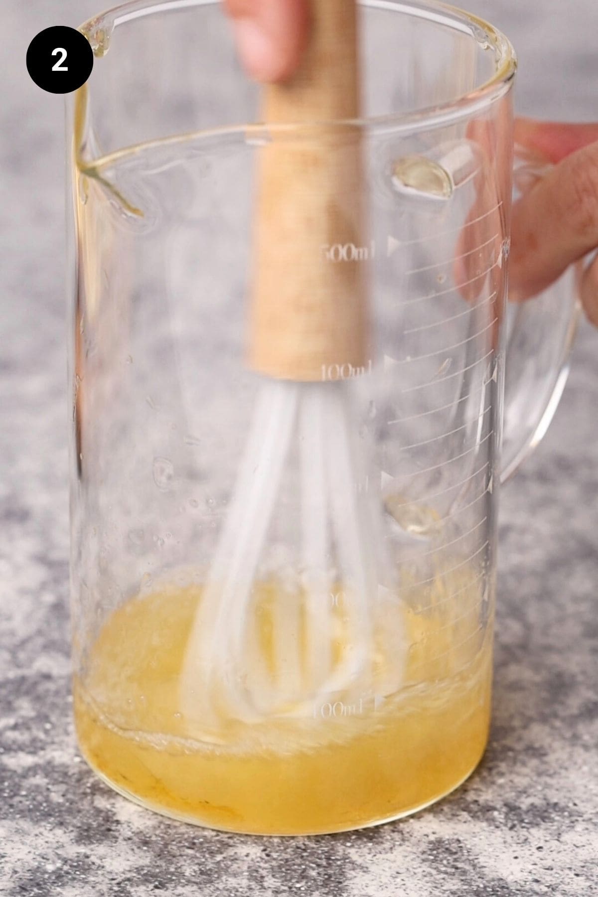 Lemon juice, honey, and salt being whisked.