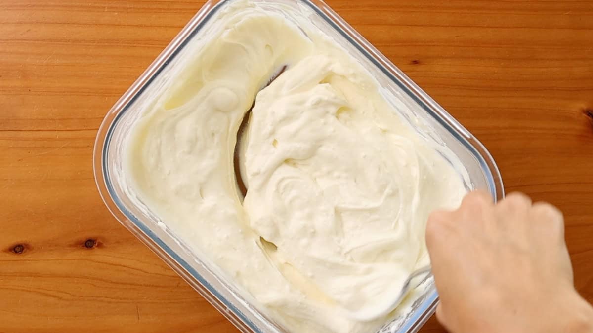 Yogurt in a glass container being stirred.