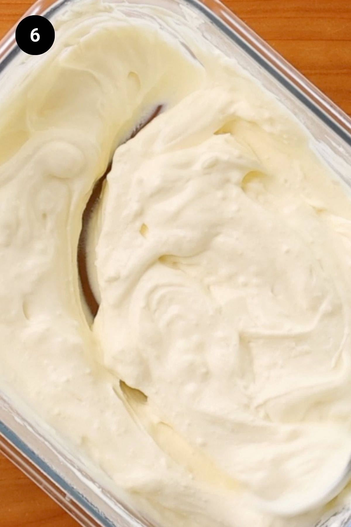 Yogurt in a glass container being stirred.