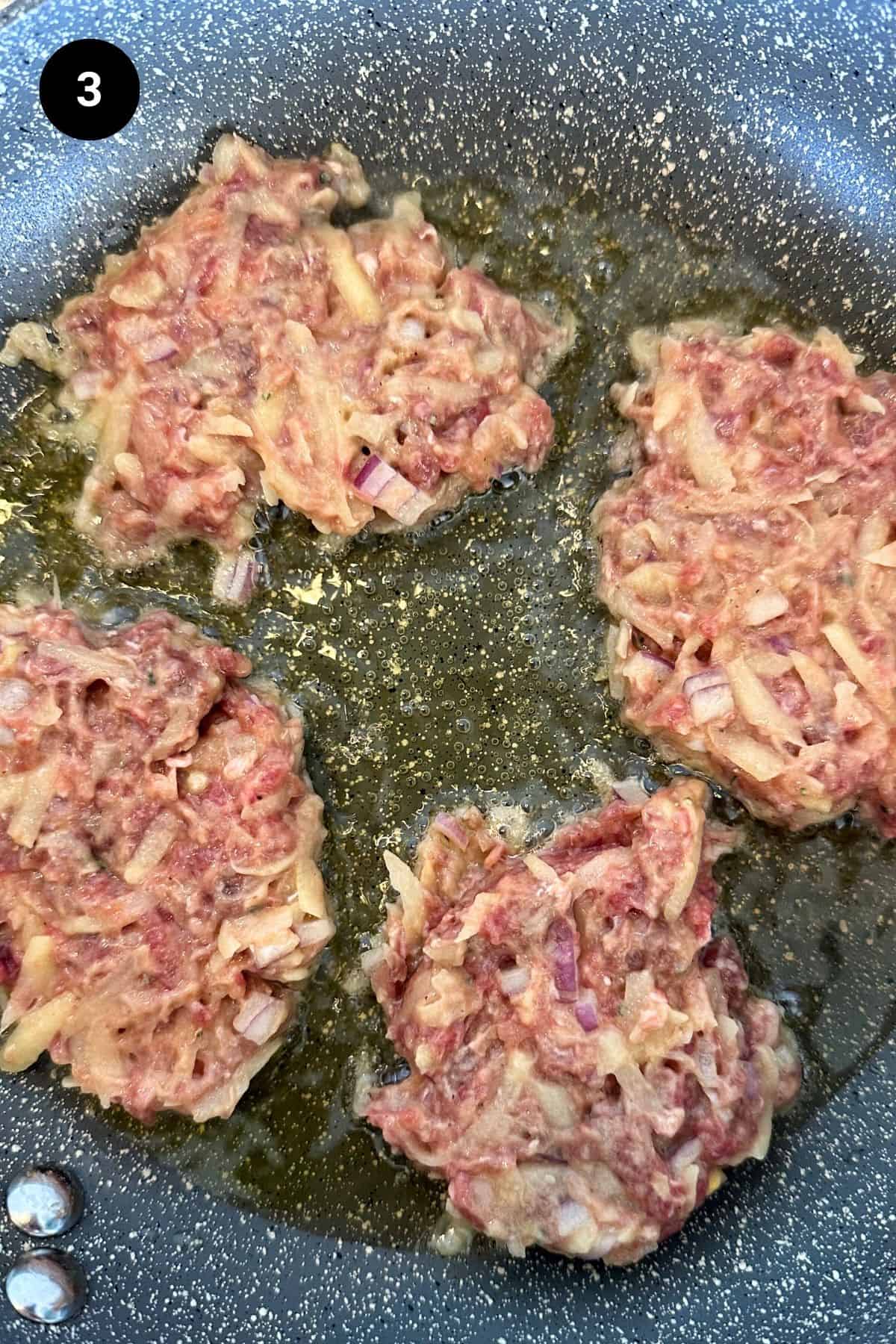 Beef fritters frying in a pan.