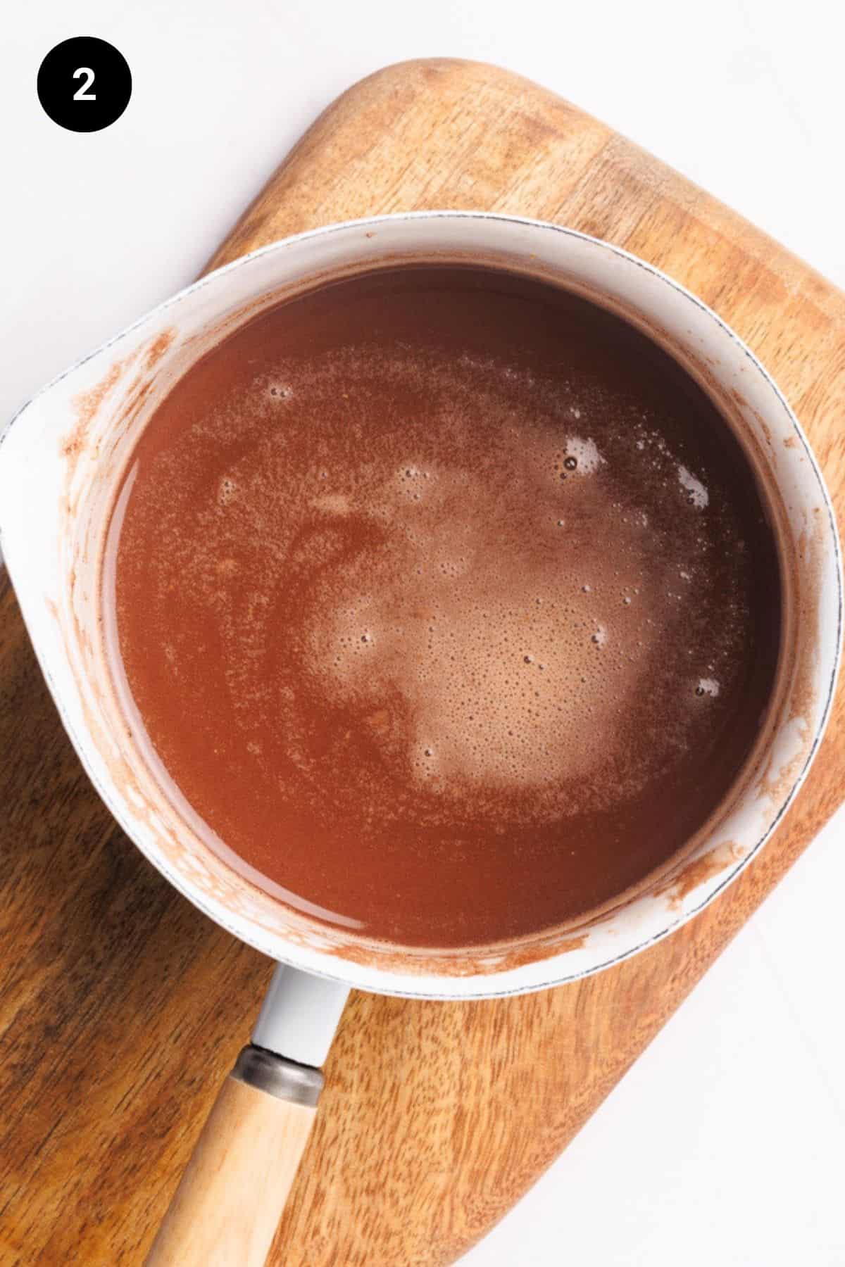 A white small saucepan filled with hot chocolate.