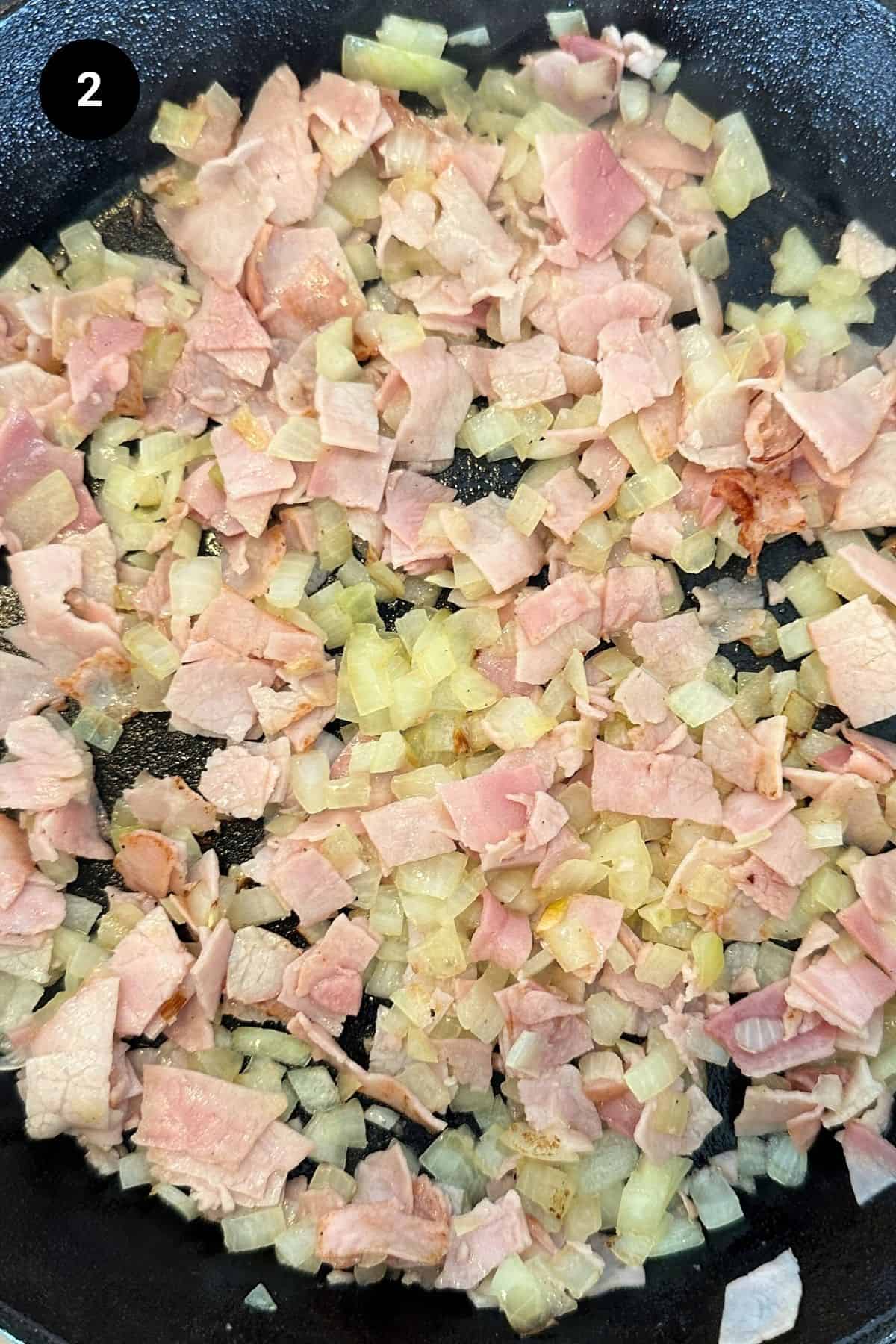 Onion and ham in a cast iron skillet.