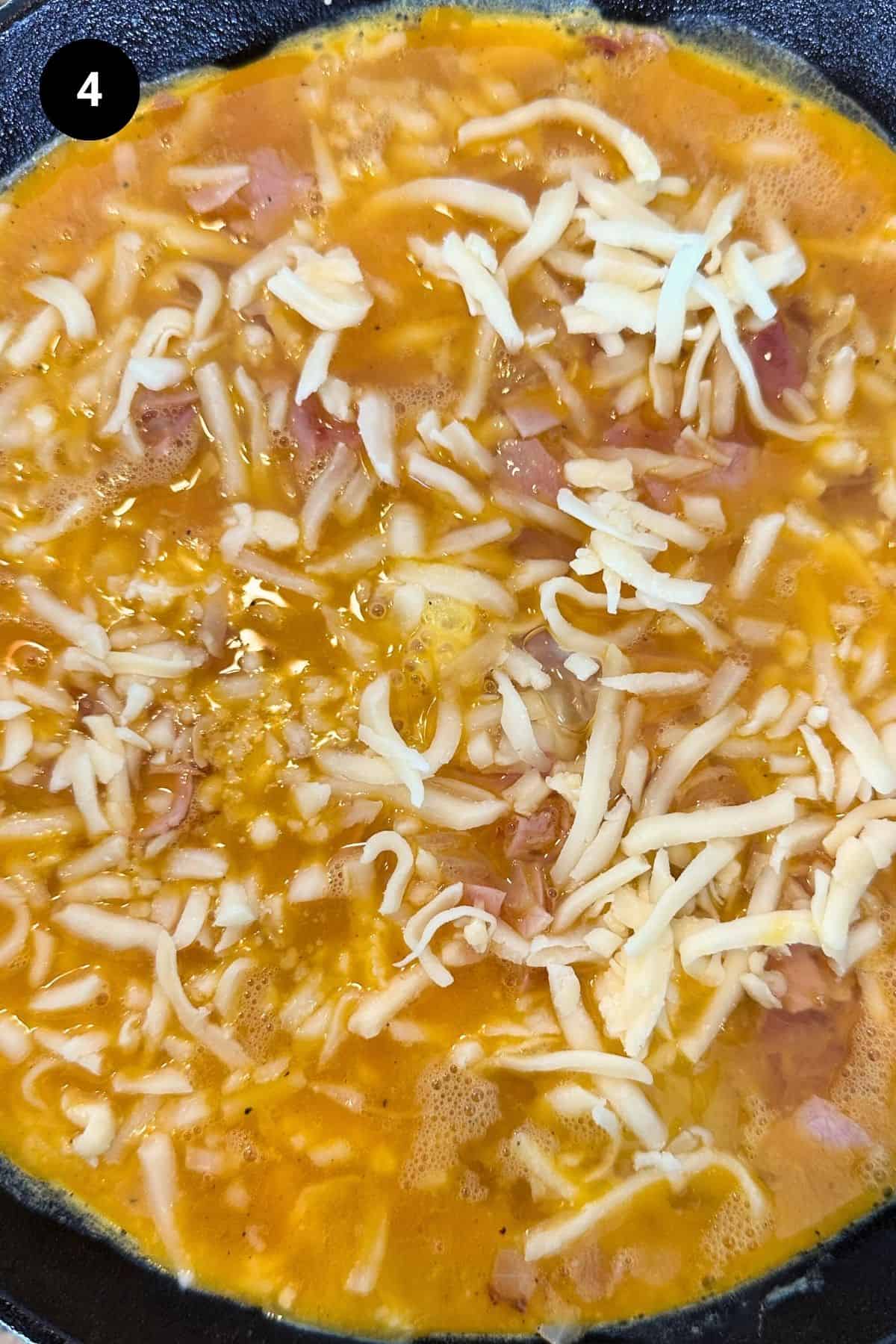 Egg mixture with cheese in a pan.