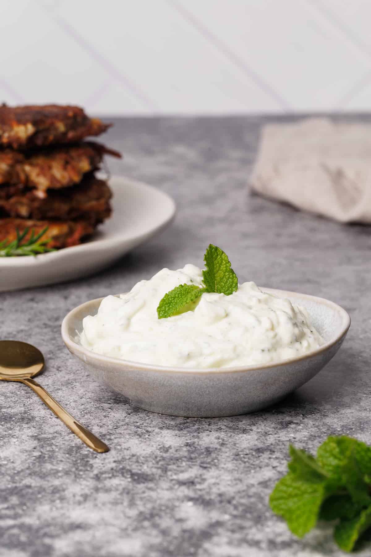 Cucumber yogurt mint sauce in a small bowl with a golden spoon.
