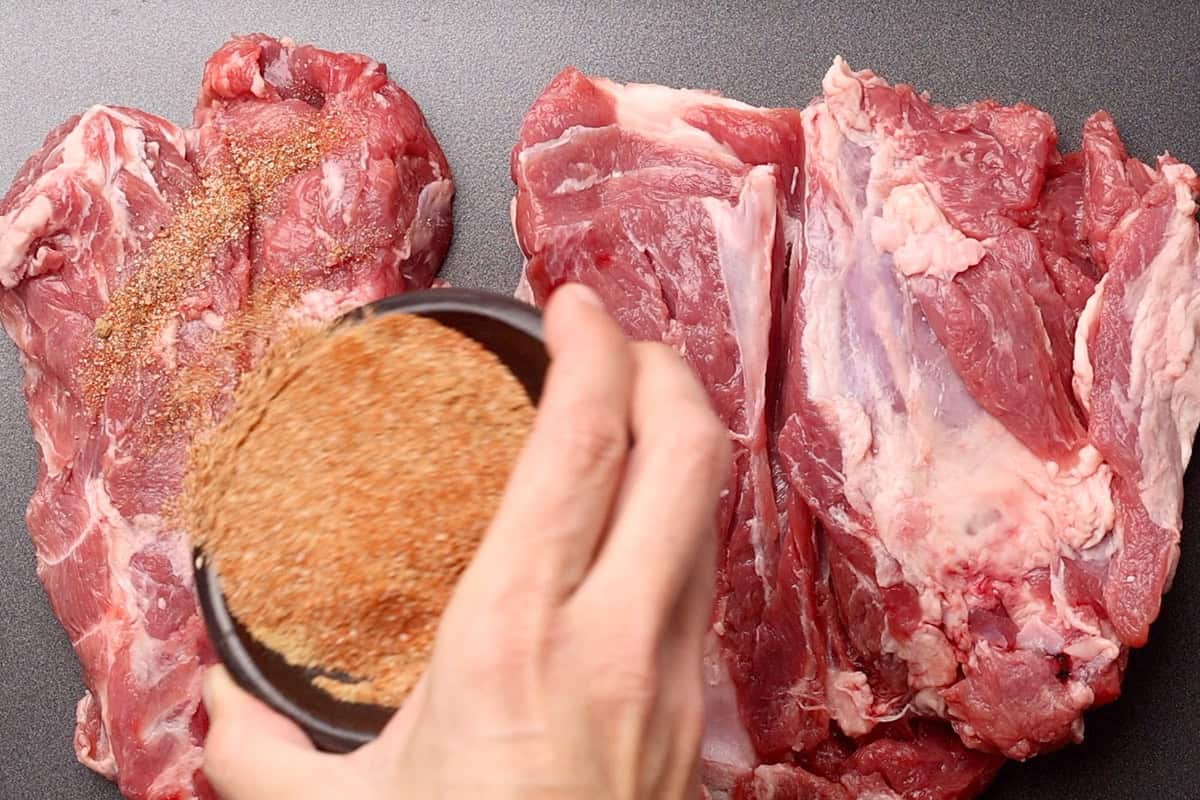 Dry rub being applied to the lamb shoulder.