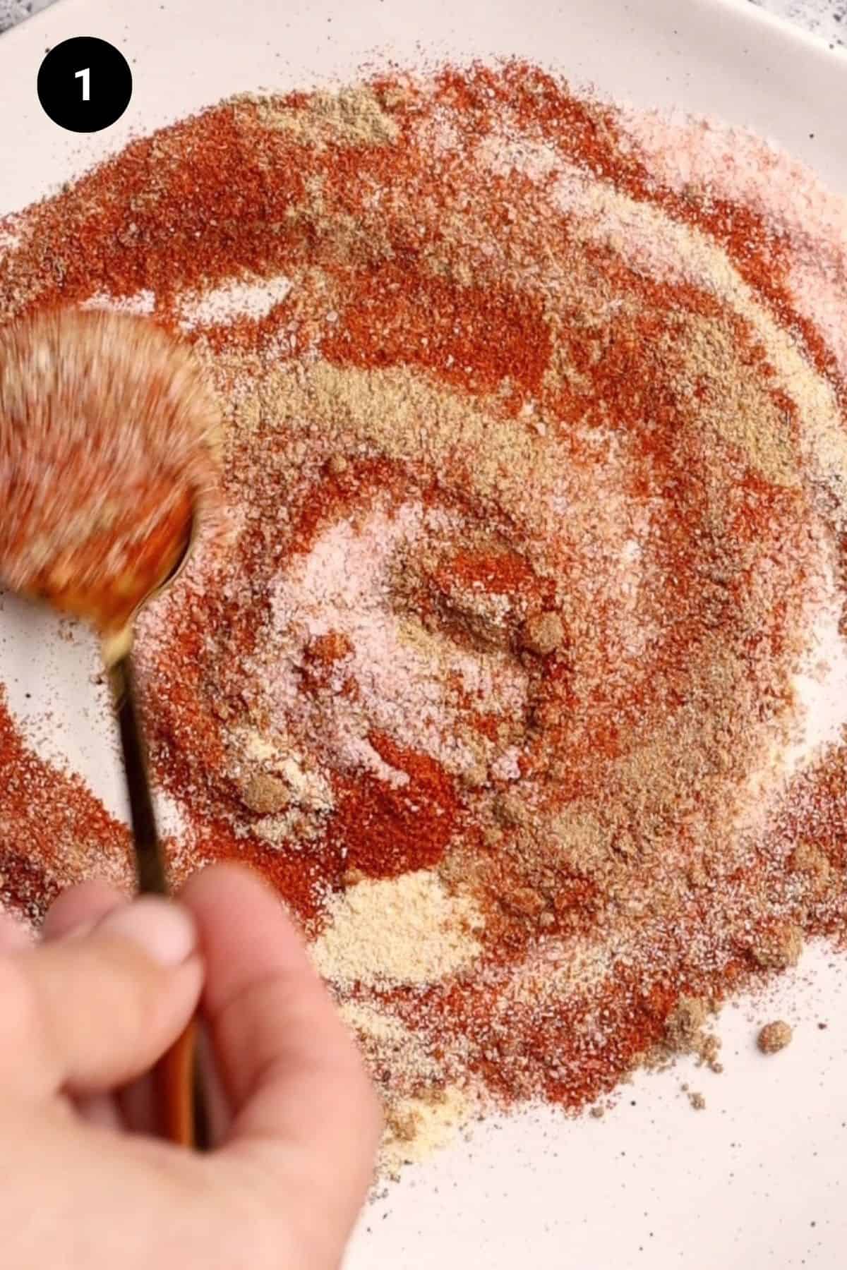 Dry rub spices being mixed with a small spoon.