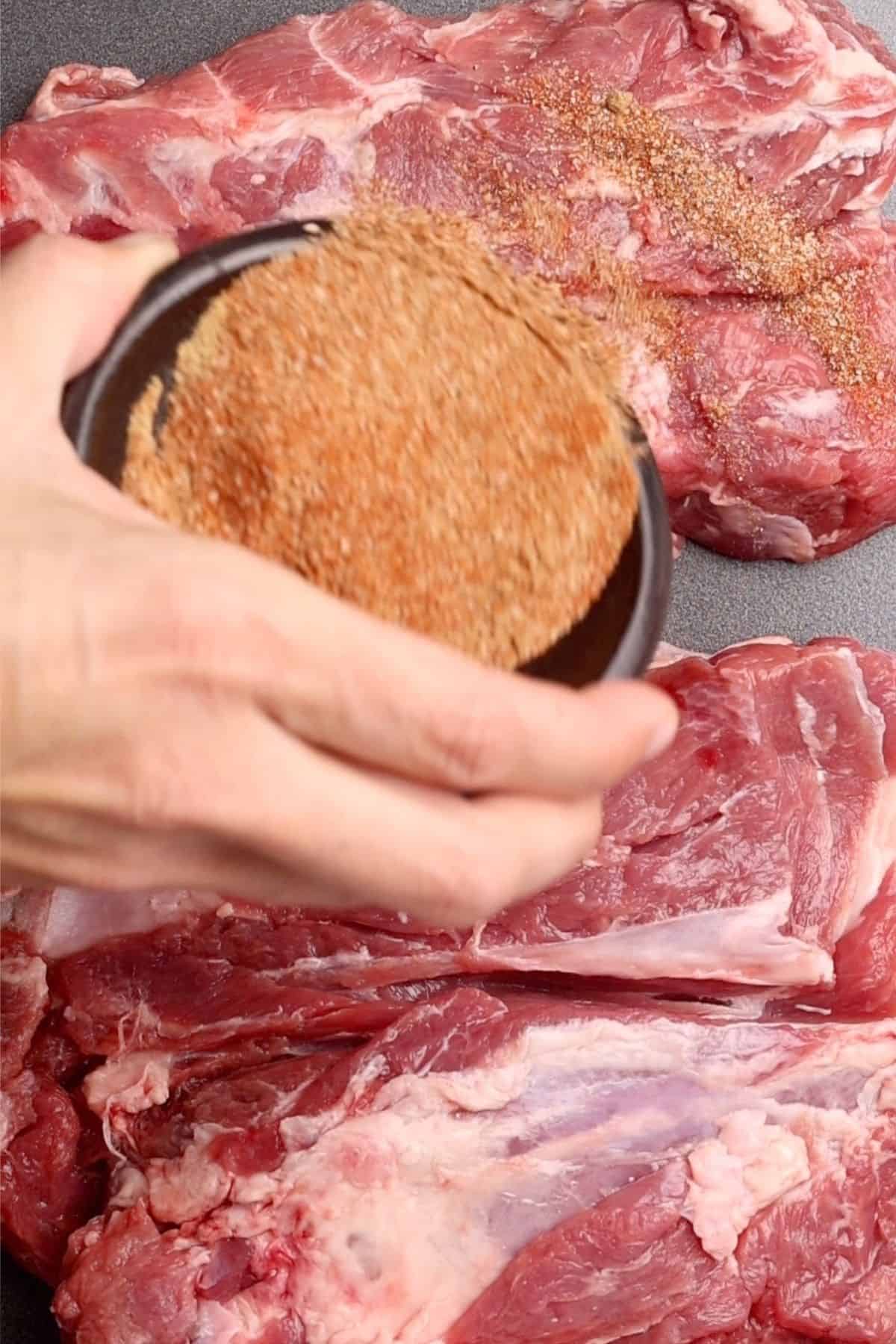Dry rub being applied to the lamb shoulder.