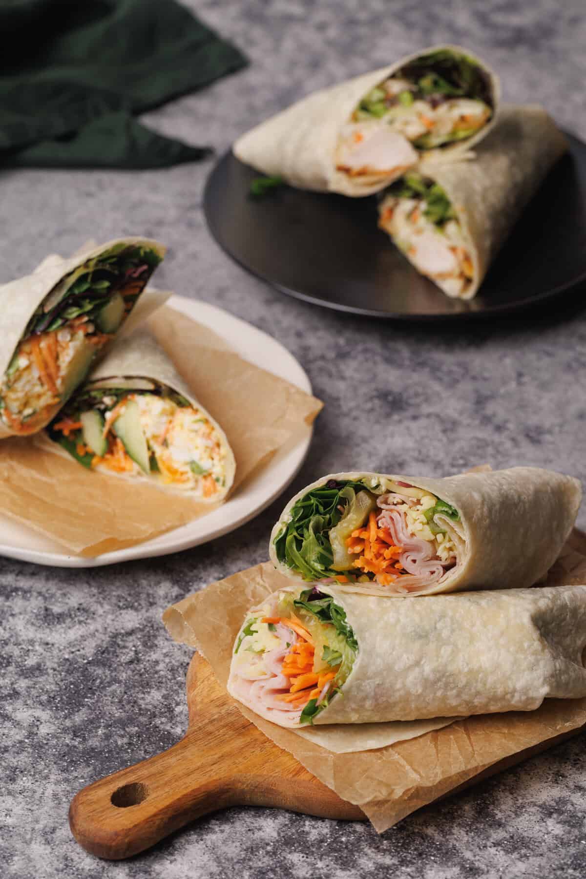 Three wraps cut open on plates.