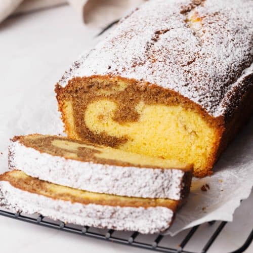 Cinnamon pound cake sliced on a wire rack next to a tea towel.