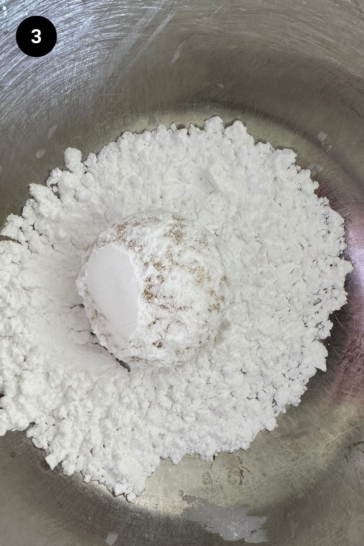 Cookie being rolled in confectioners sugar.