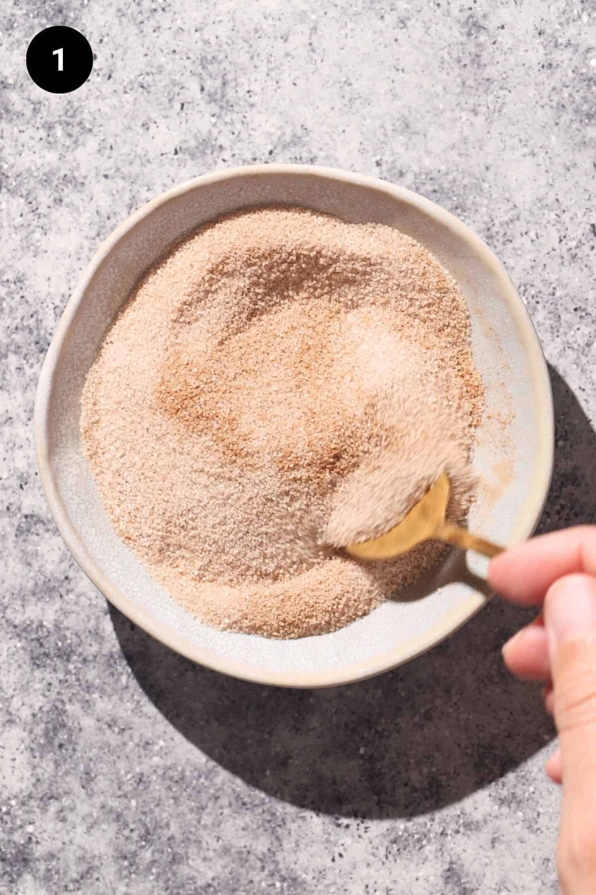 Cinnamon sugar in a small bowl being stirred.