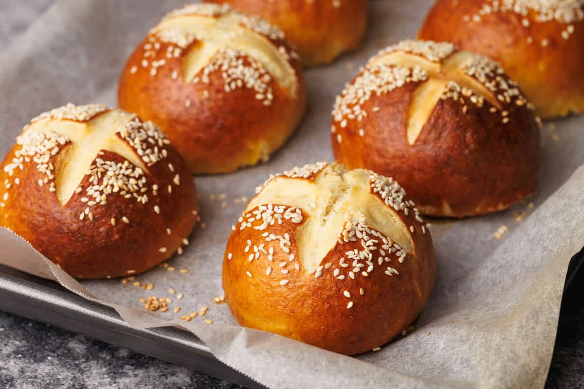 Pretzel buns on a baking tray just after being baked.