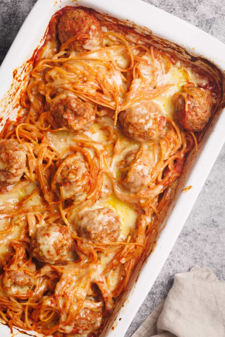 Spaghetti and meatballs baked in a white casserole dish, covered with melted cheese.