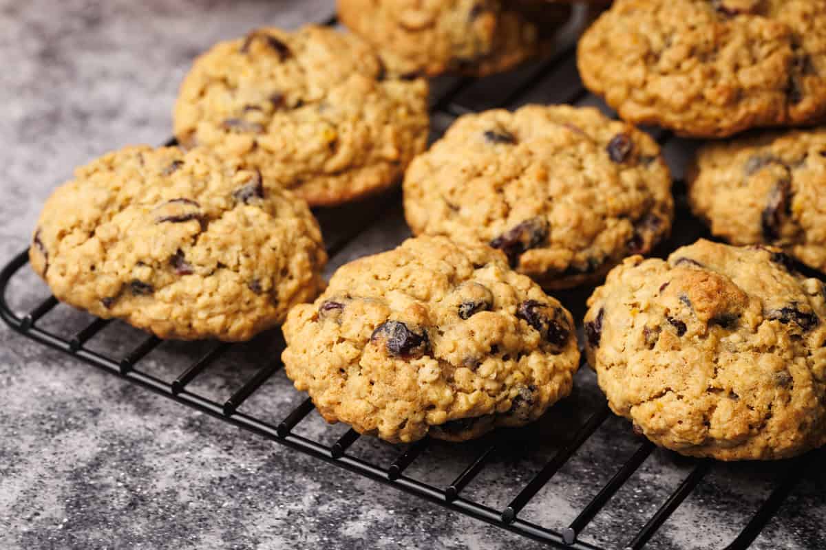 Oatmeal cookies on a cooling rack next to linen towel.