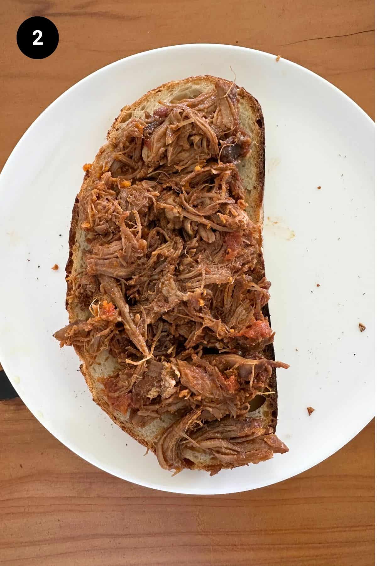Bread slice on a white plate with fillings.