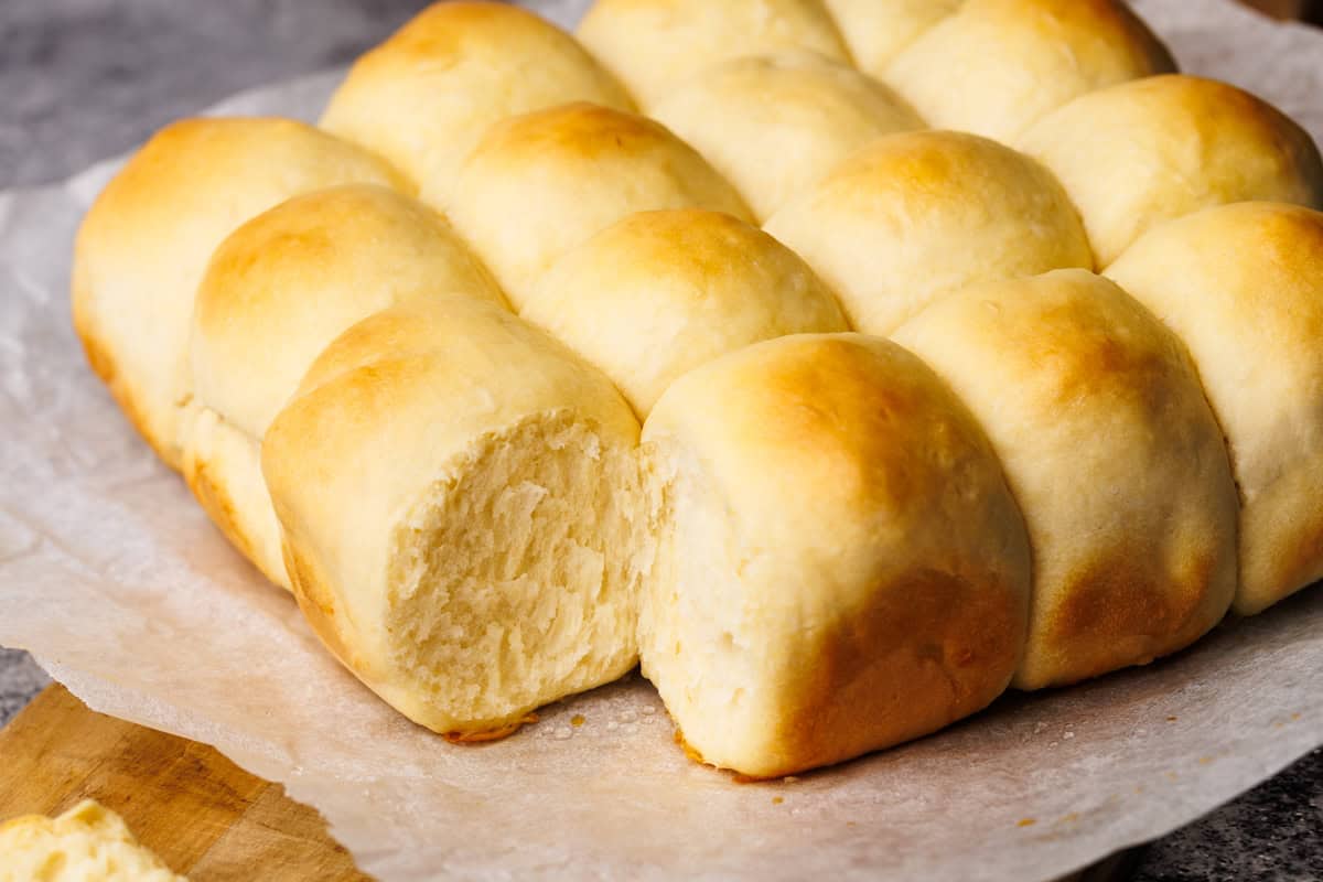 Dinner rolls on a parchment paper lined wooden board.
