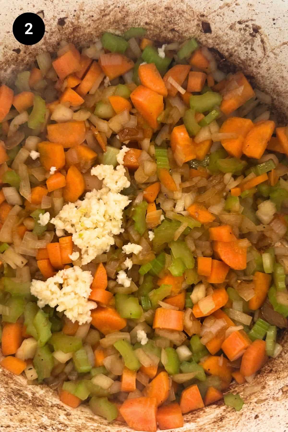 Cooked soffritto with freshly minced garlic in a pot.