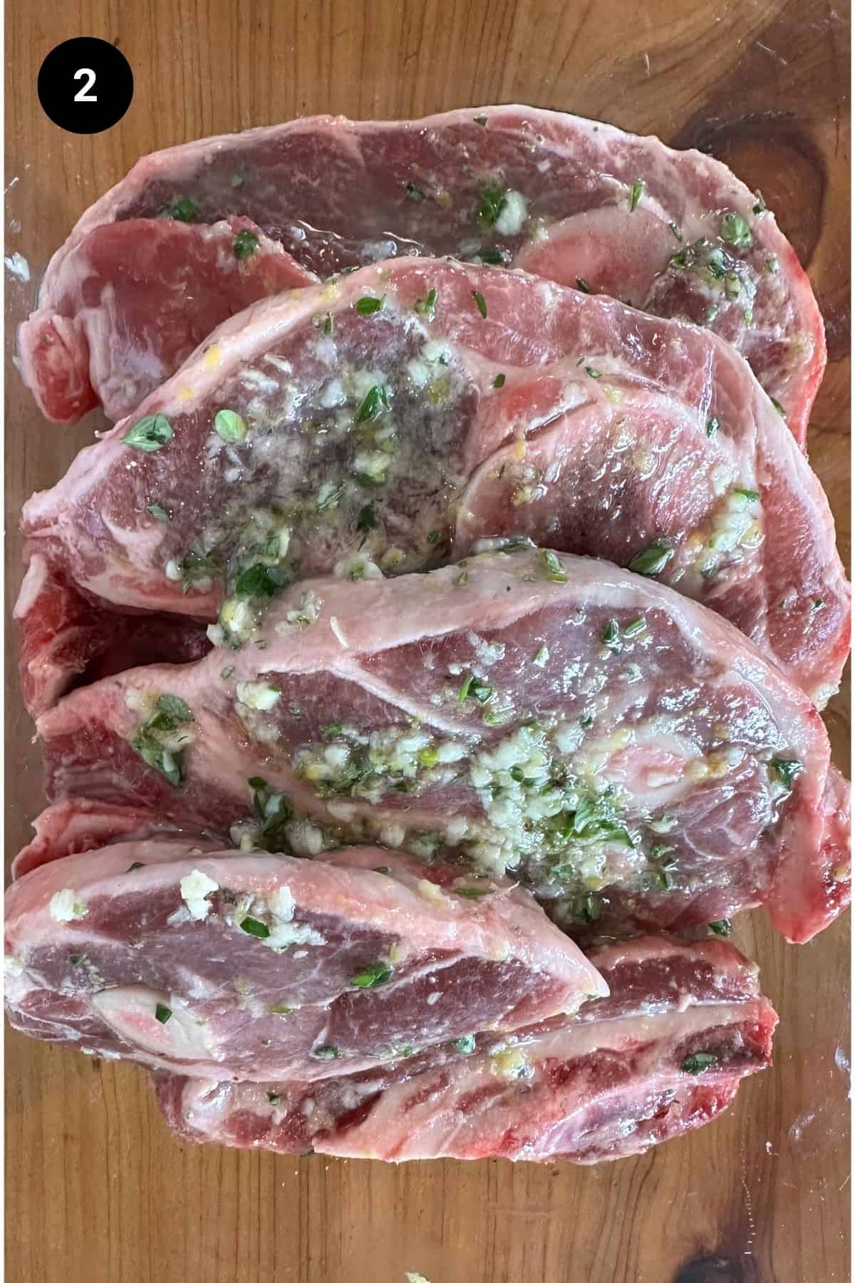 Marinated lamb shoulder chops in a glass bowl.