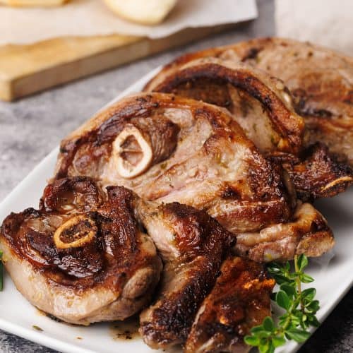 Pan-fried lamb shoulder chops on a white plate.