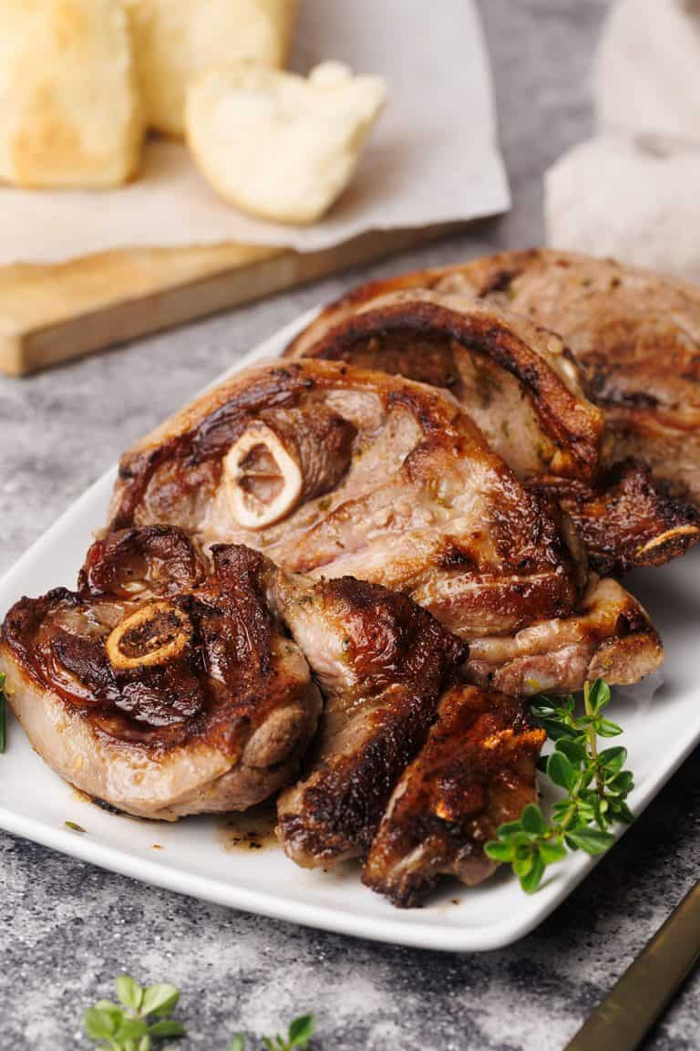 Pan-fried lamb shoulder chops on a white plate.