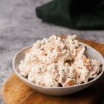 Smoked chicken salad in a small bowl on a wooden board.