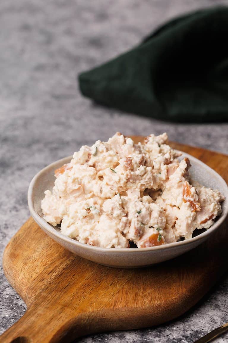 Smoked chicken salad in a small bowl on a wooden board.