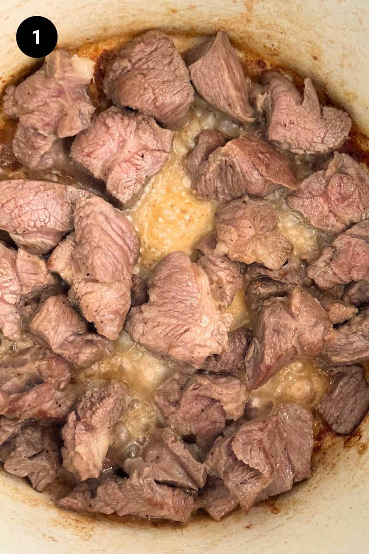 Diced lamb browned in a Dutch oven.