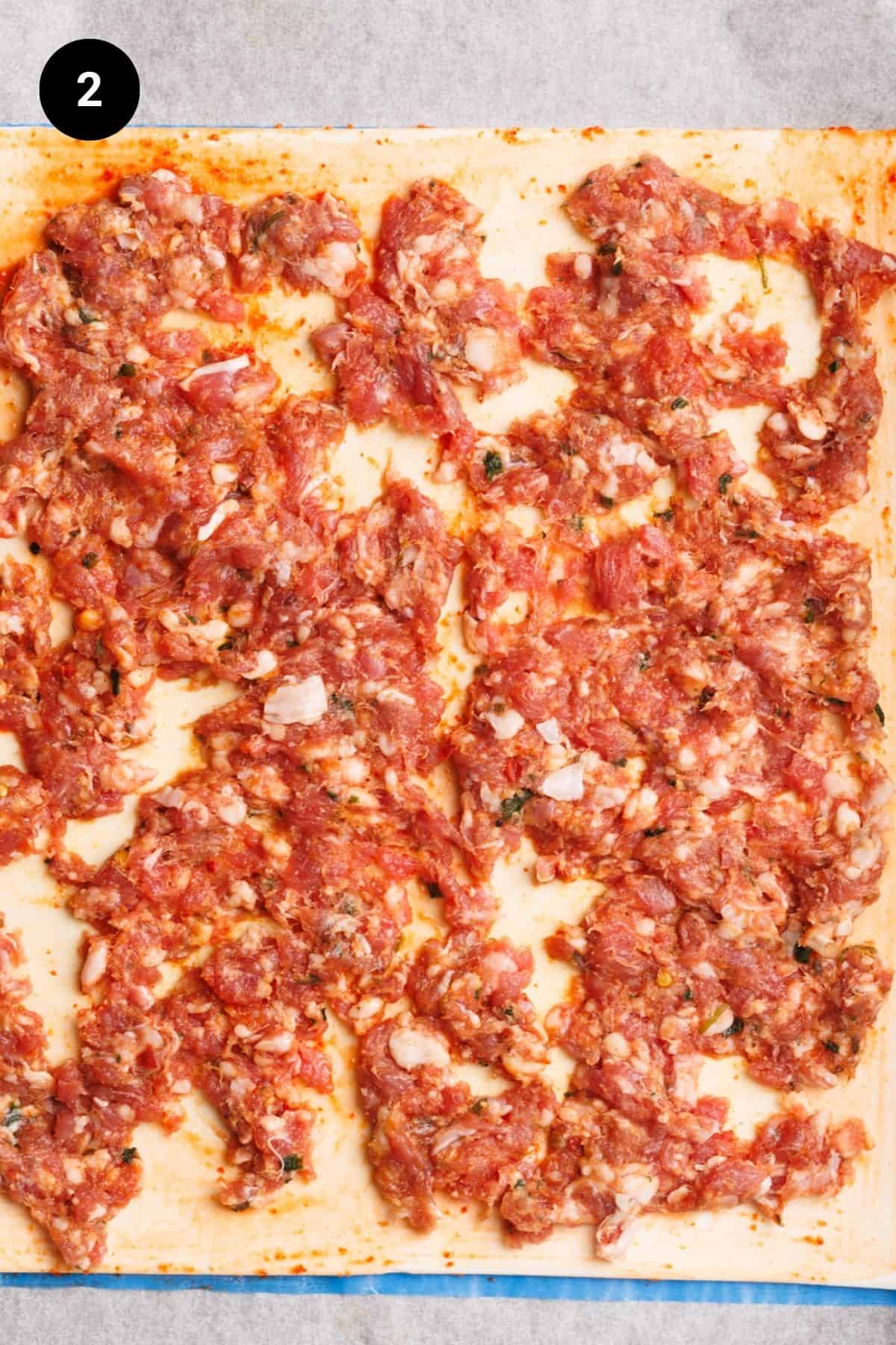 Puff pastry sheet covered in lamb sausage meat.
