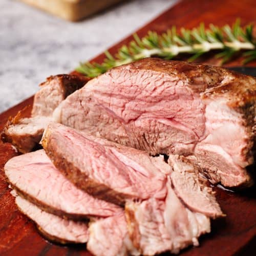 Lamb roast sliced up on a wooden board.
