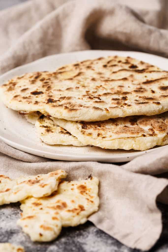 Flatbreads on a plate wrapped in a tea towel.