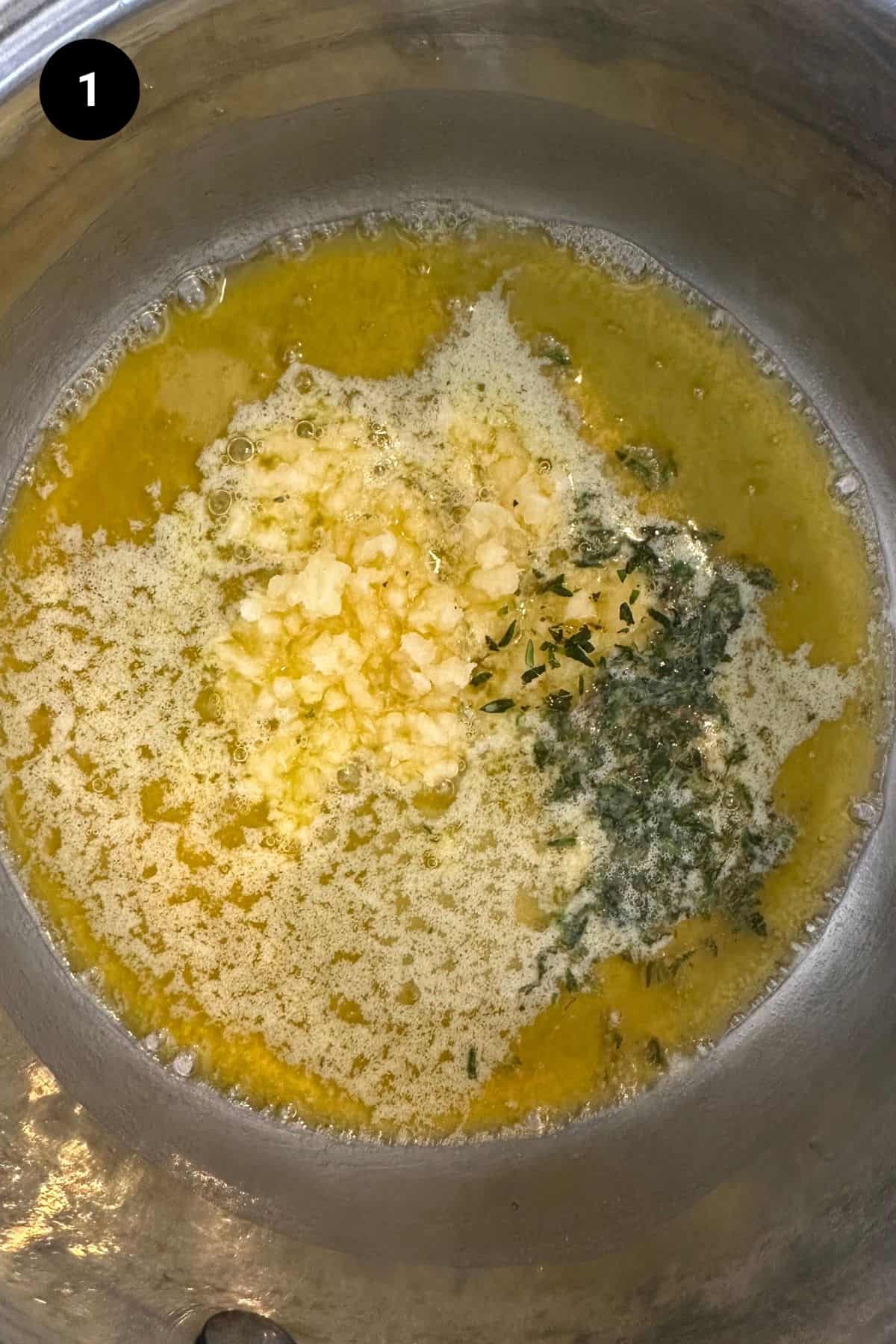 Garlic and thyme added to melted butter in a small saucepan.