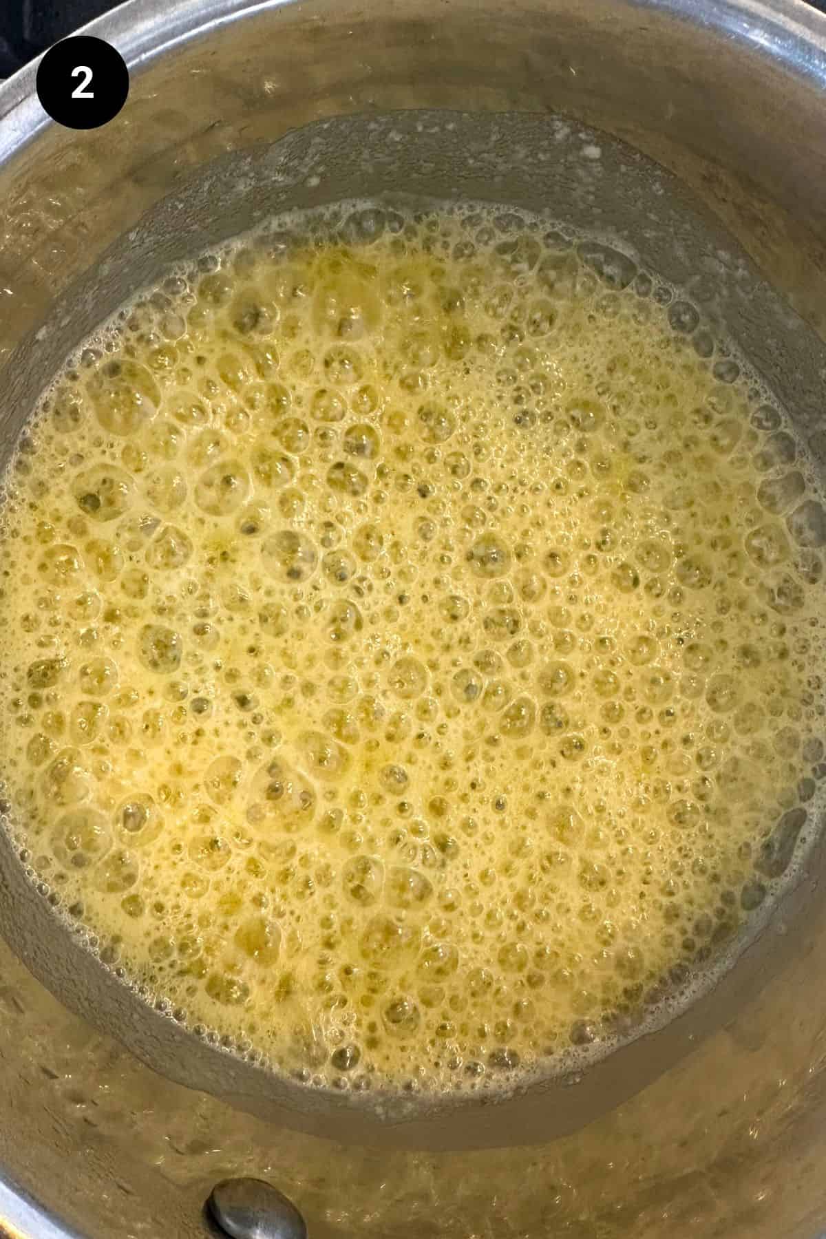 Garlic and thyme cooking in melted butter in a small saucepan.