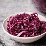 Red cabbage salad in a white bowl.