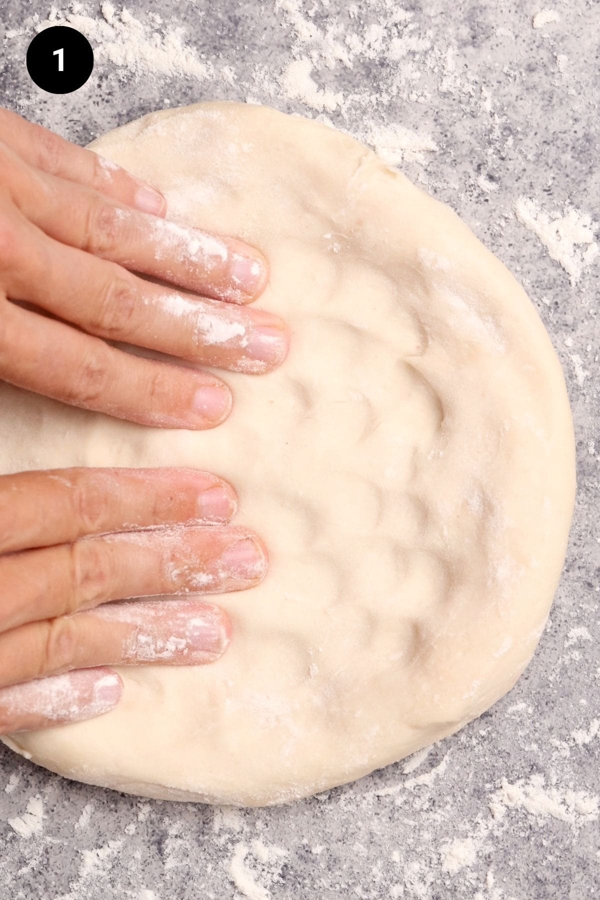 Pizza dough being shaped by hand.