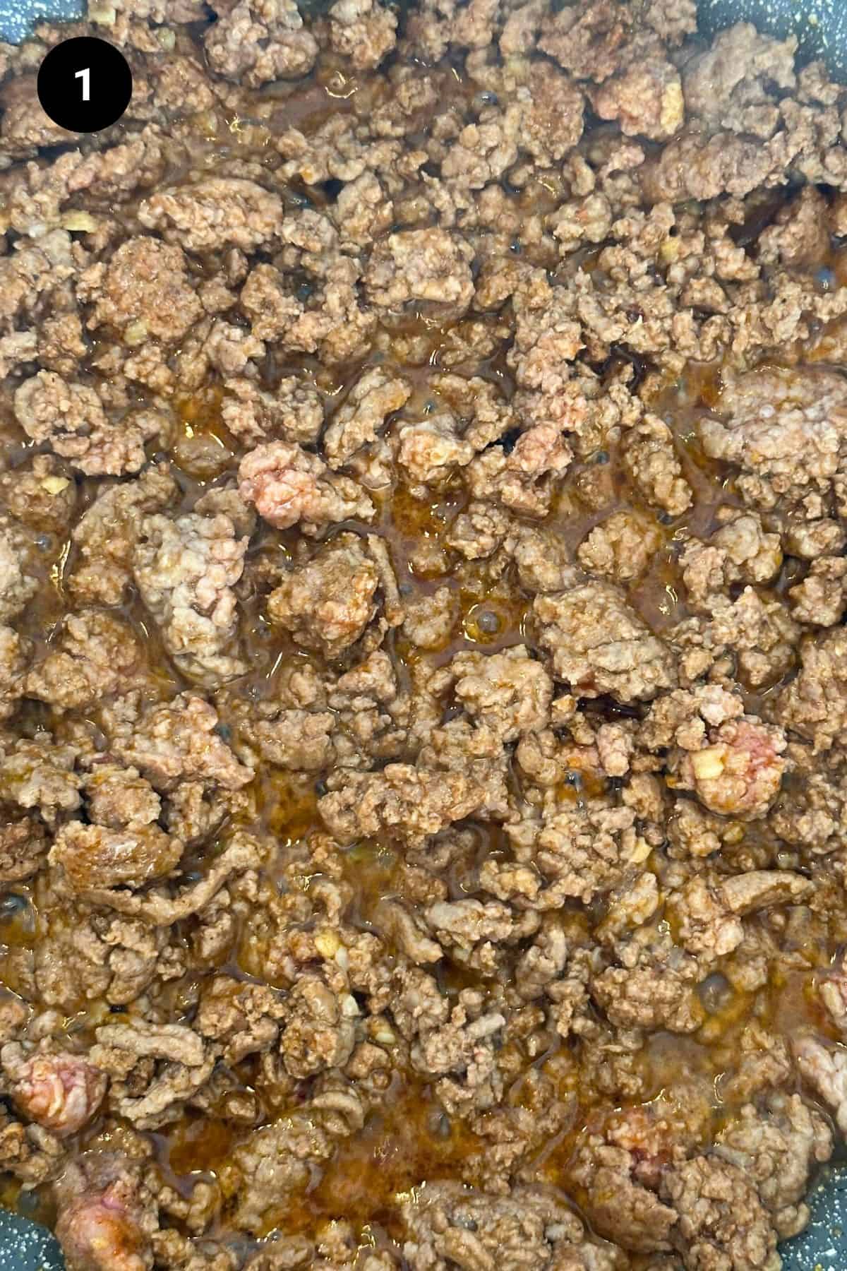 Close-up of lamb browning in a pan.