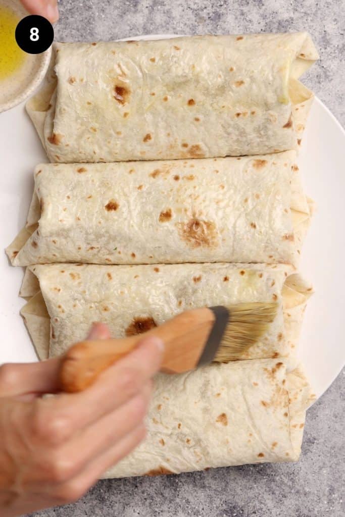 Burritos being brushed with oil.