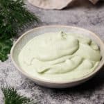 Ranch dip in a small bowl next to fresh herbs and a linen tea towel.