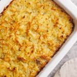 Hash brown beef casserole in a white casserole dish next to a linen towel.