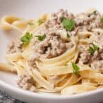 Hamburger Alfredo pasta in white bowl.