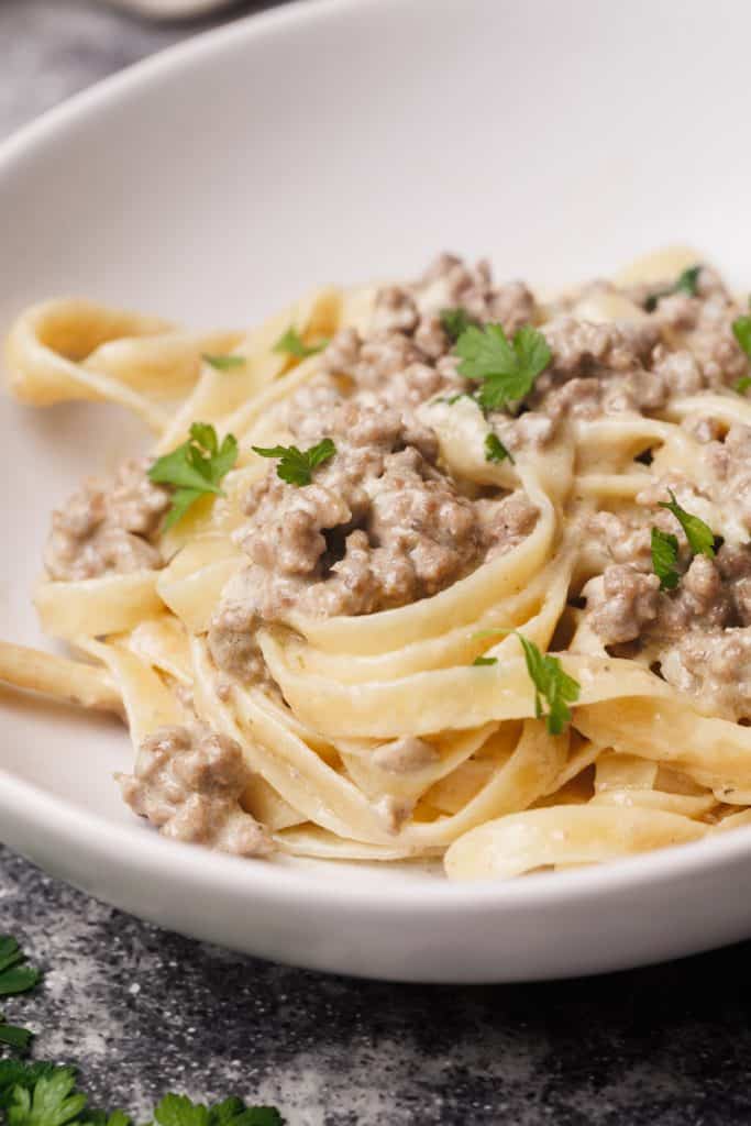 Hamburger Alfredo pasta in white bowl.