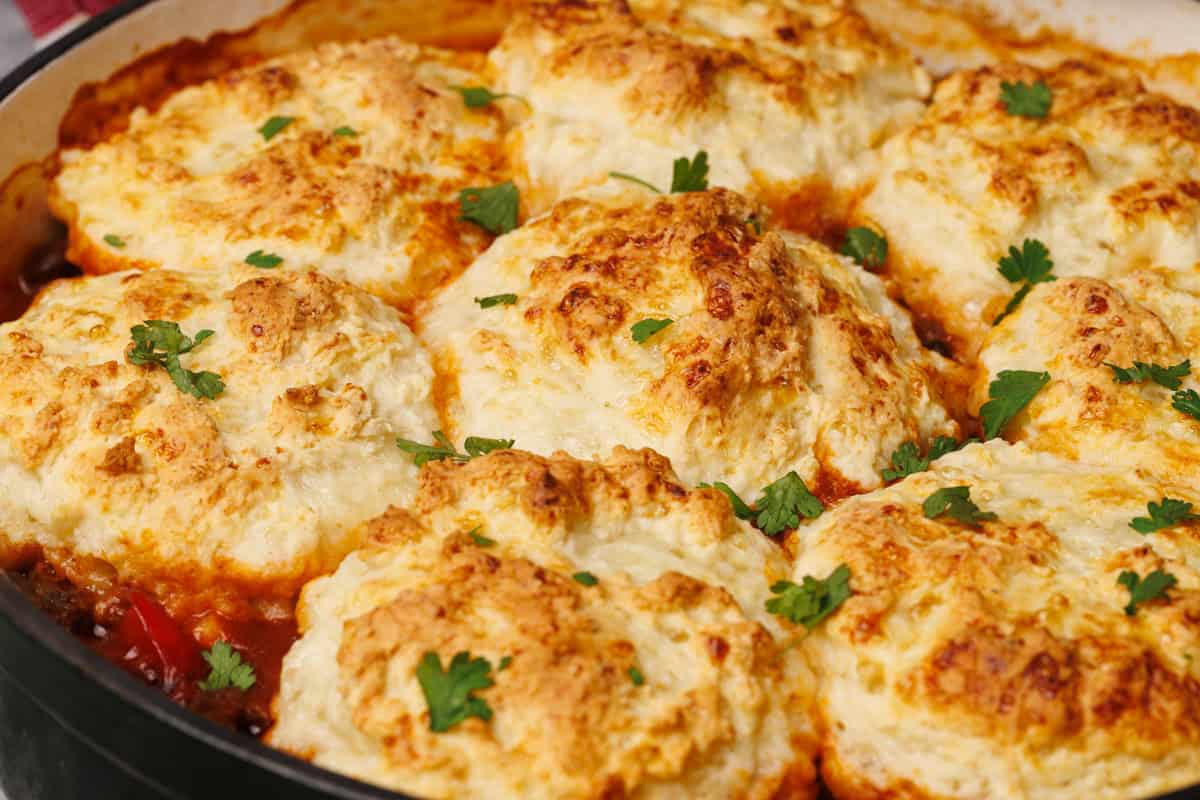 Cowboy casserole with biscuits in a Dutch oven.